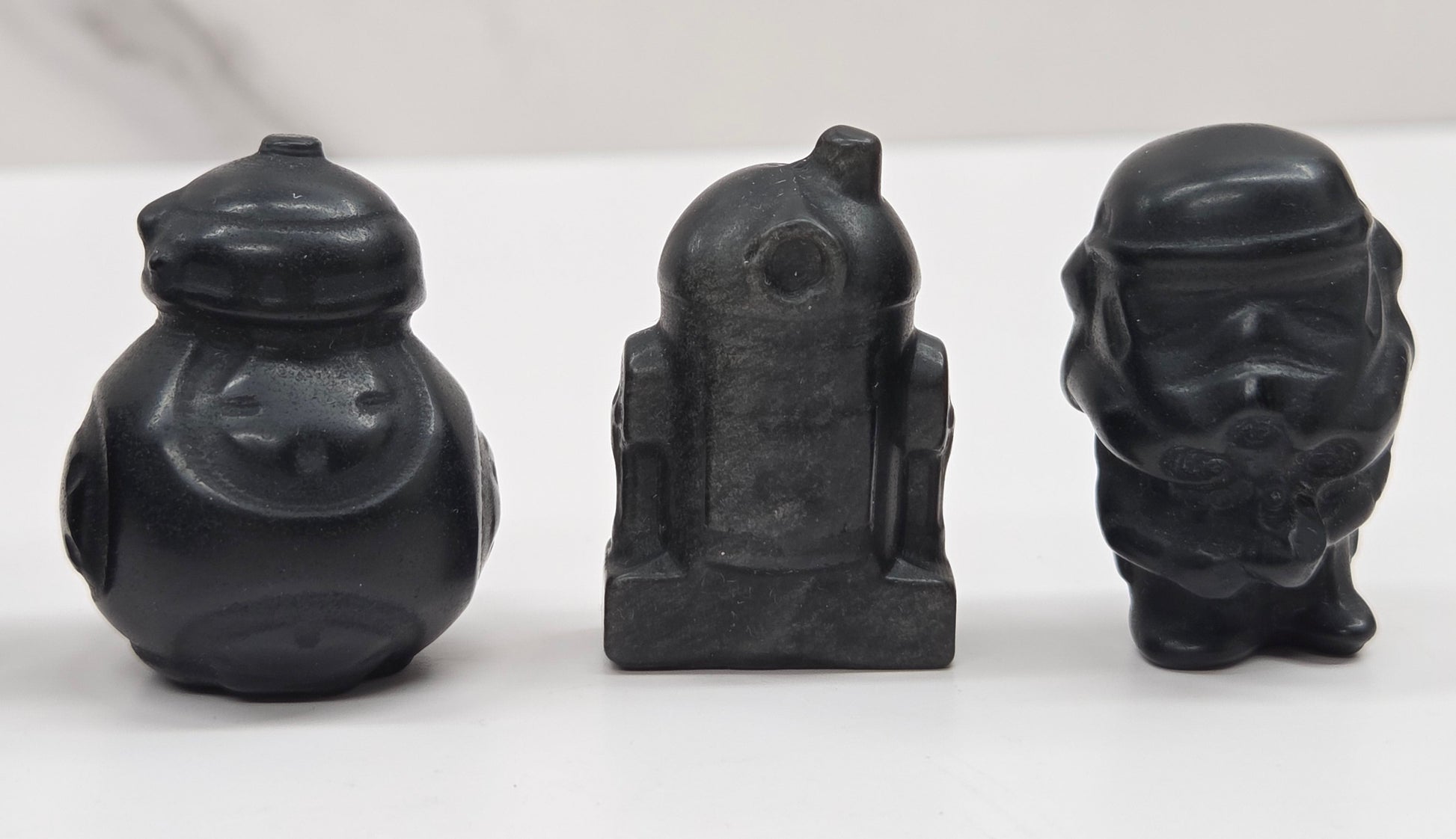 Set of Star Wars character carvings made of Obsidian on a white background