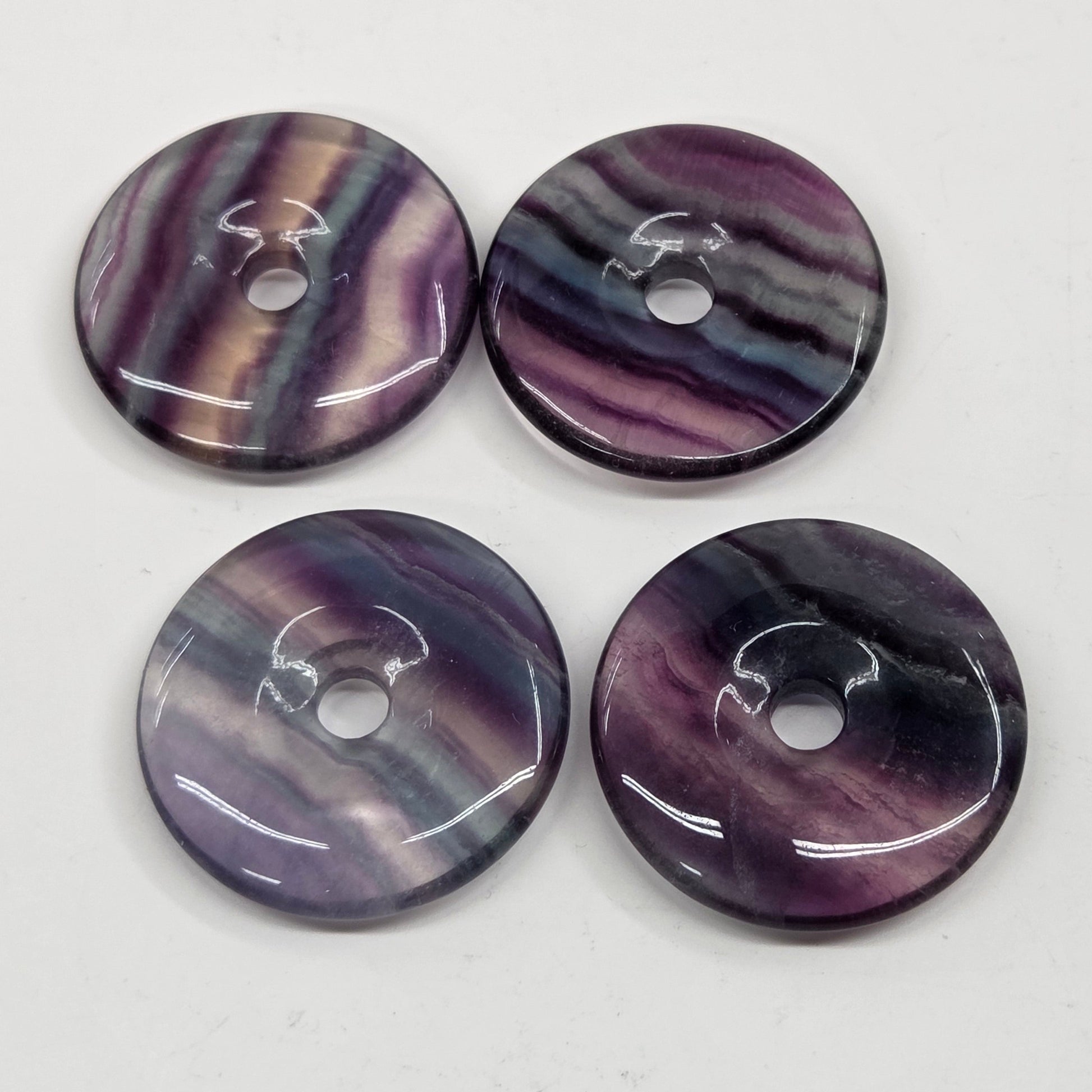 Multi-colored fluorite donut shaped carvings with banding on a white background