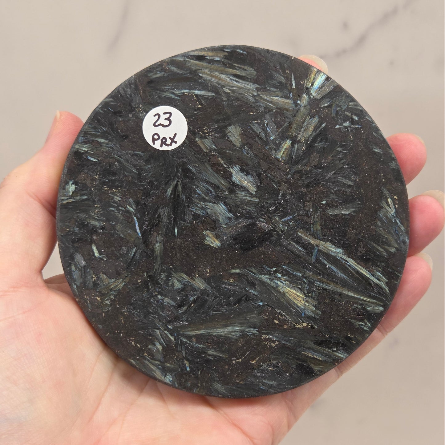 Astrophyllite round carving with varying colors against a white background