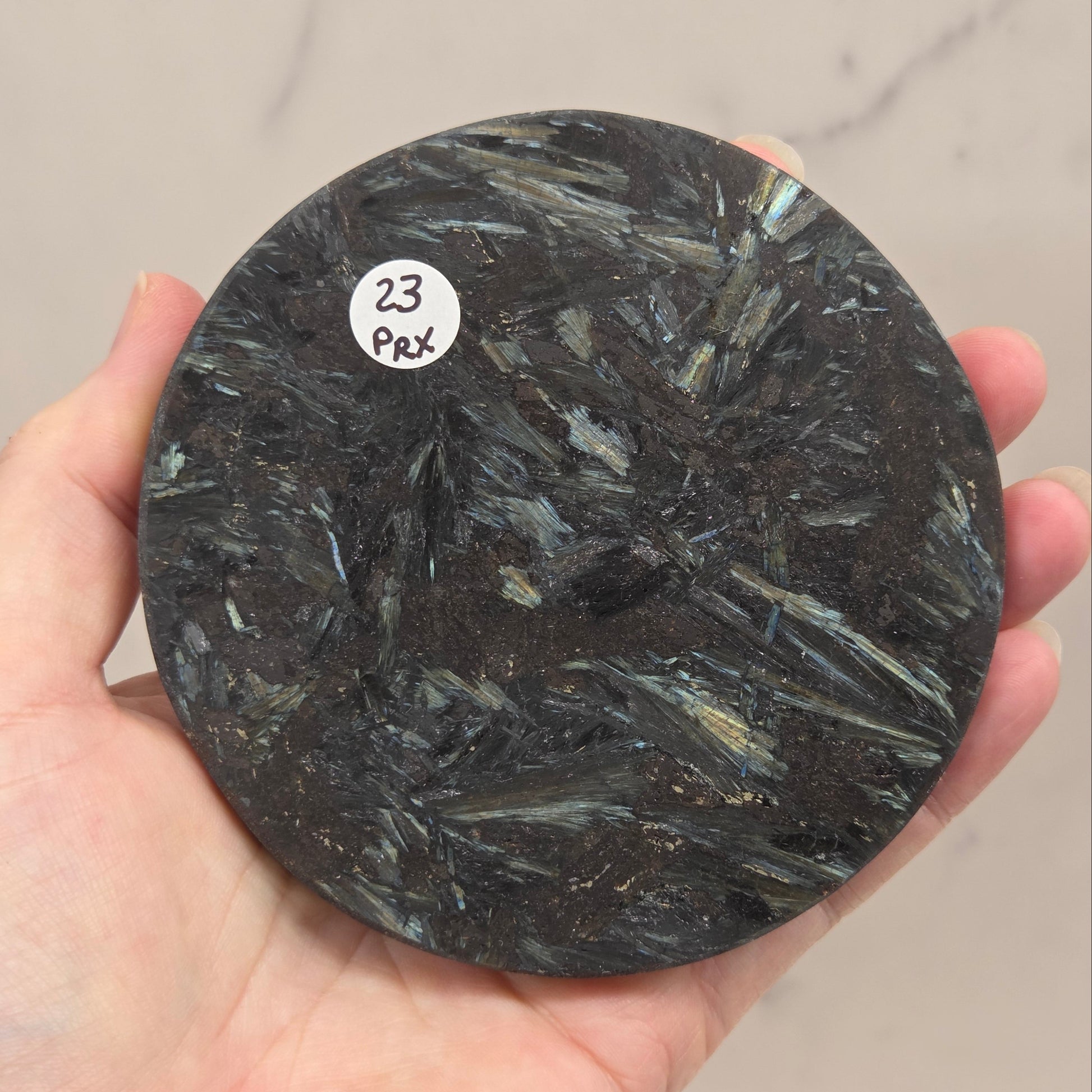 Astrophyllite round carving with varying colors against a white background