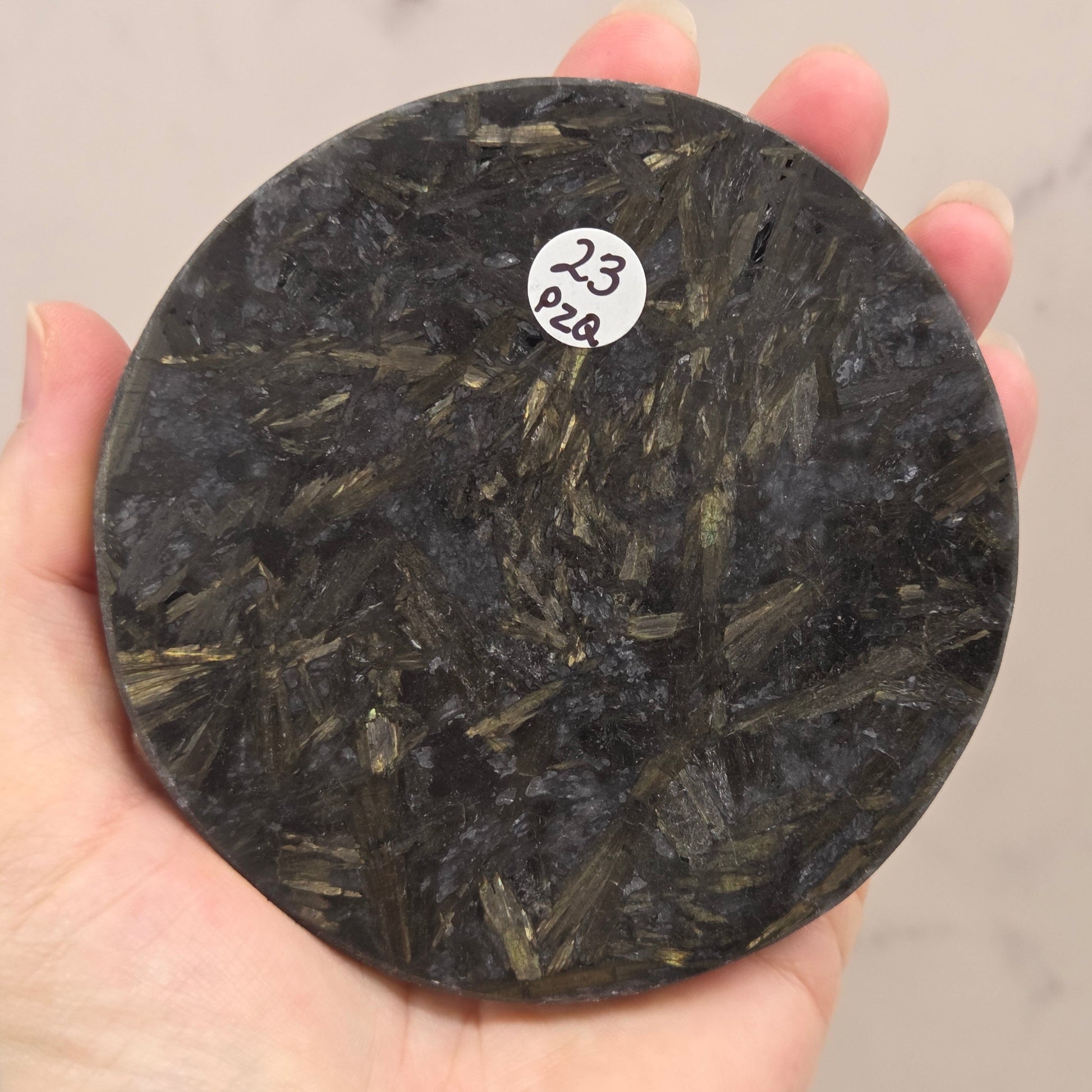Astrophyllite round carving with varying colors aagainst a white background