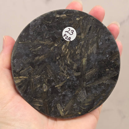 Astrophyllite round carving with varying colors aagainst a white background