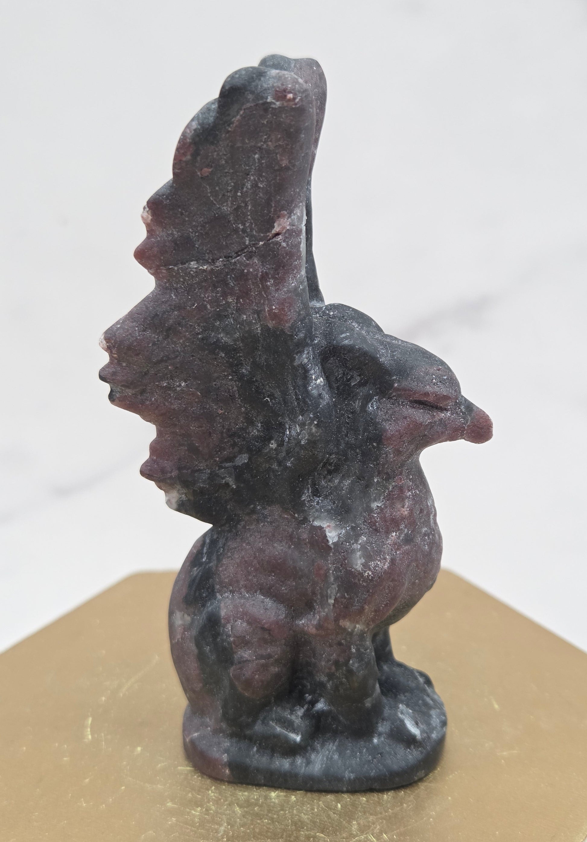 Garnet griffon carving on a wood stand against a white background