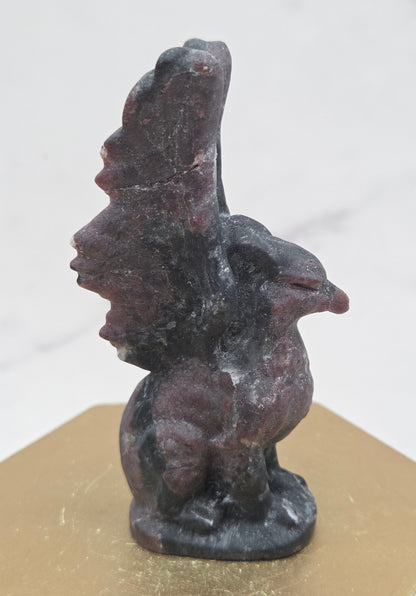 Garnet griffon carving on a wood stand against a white background