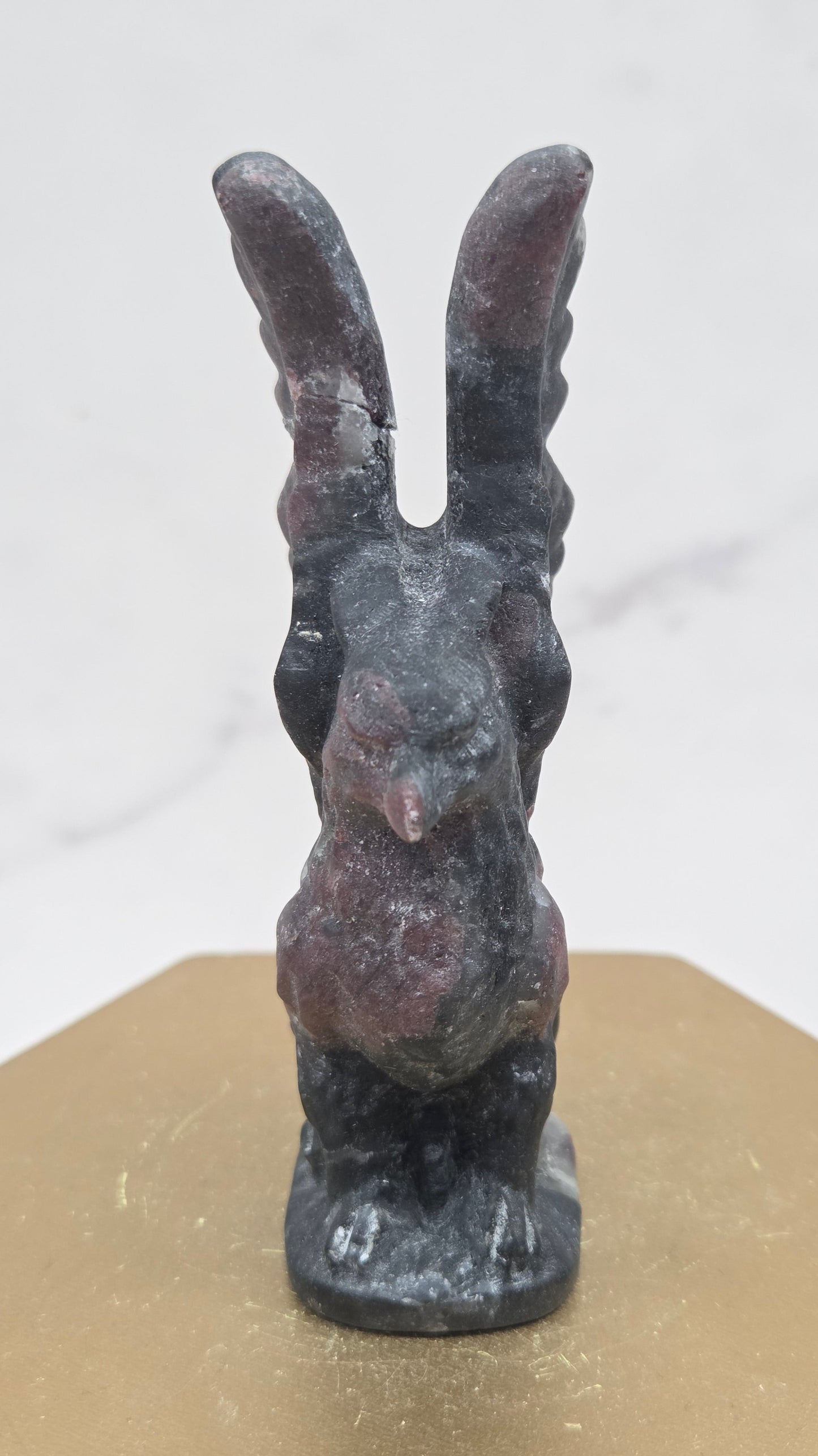 Garnet griffon carving on a wood stand against a white background