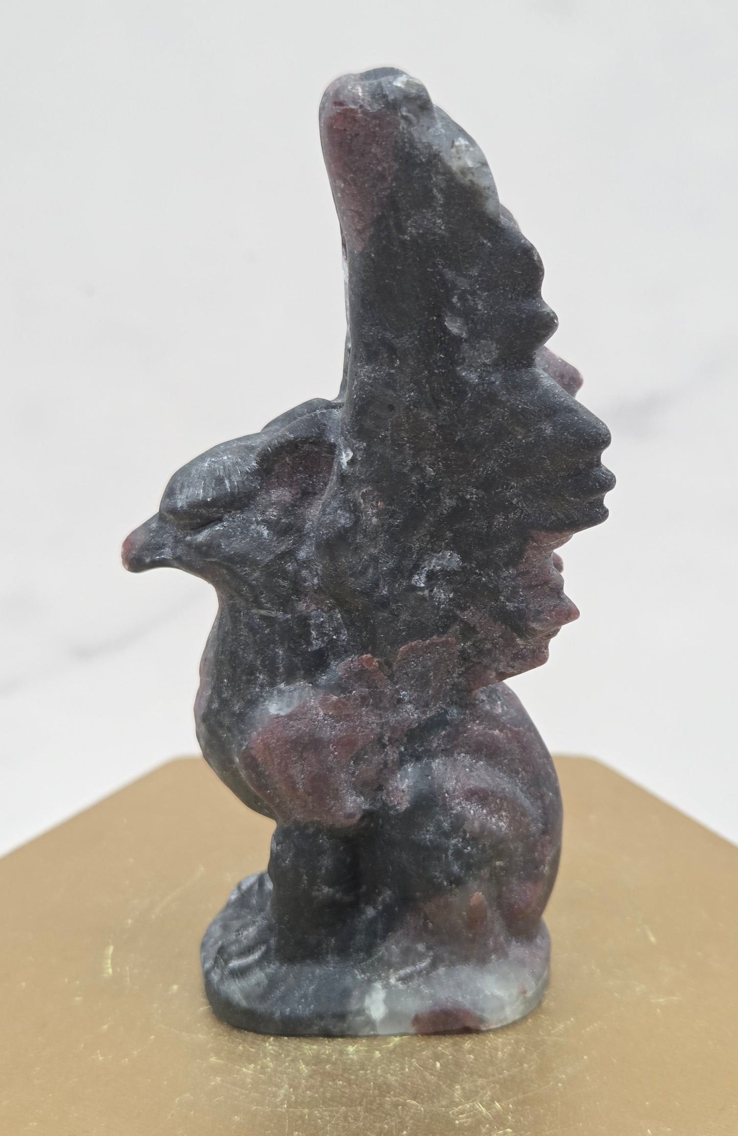 Garnet griffon carving on a wood stand against a white background