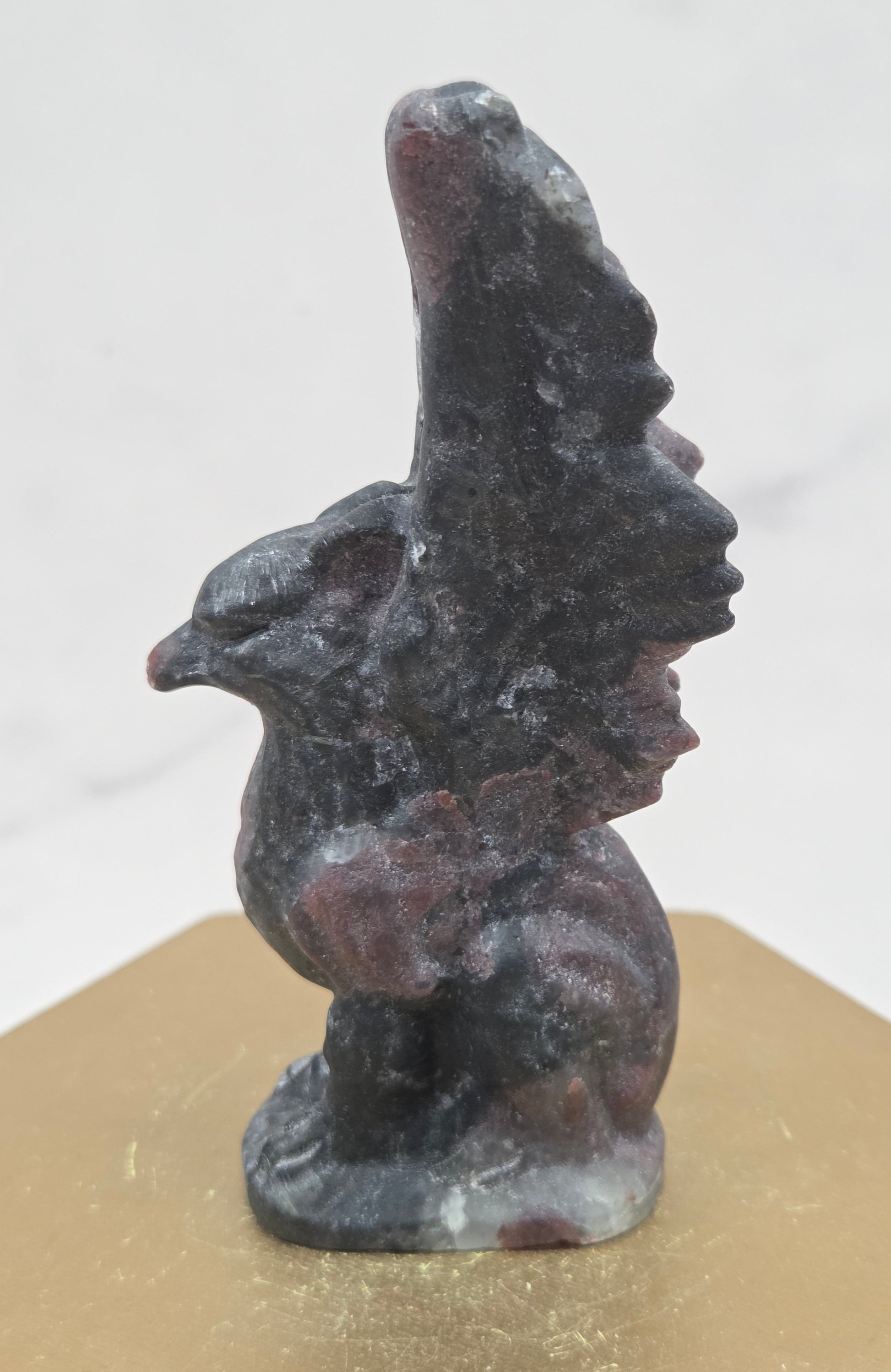 Garnet griffon carving on a wood stand against a white background