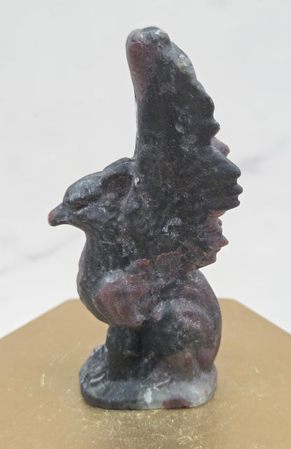 Garnet griffon carving on a wood stand against a white background
