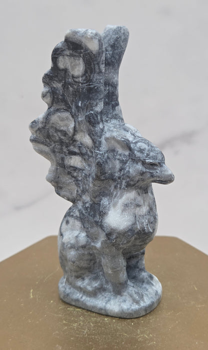 Fossil Jasper griffon carving on a wood stand against a white background