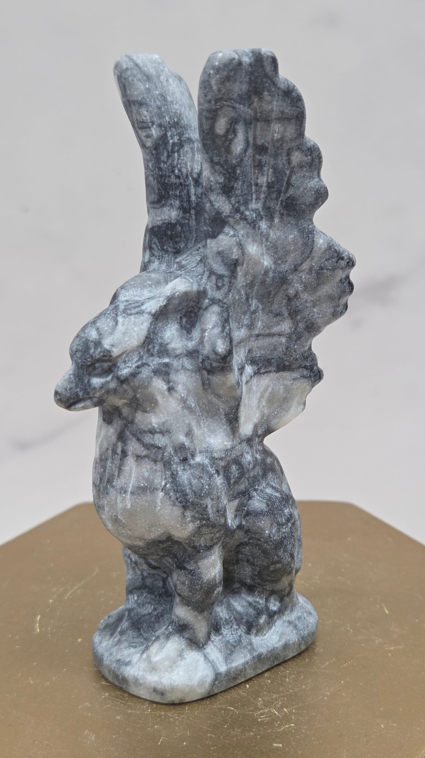 Fossil Jasper griffon carving on a wood stand against a white background