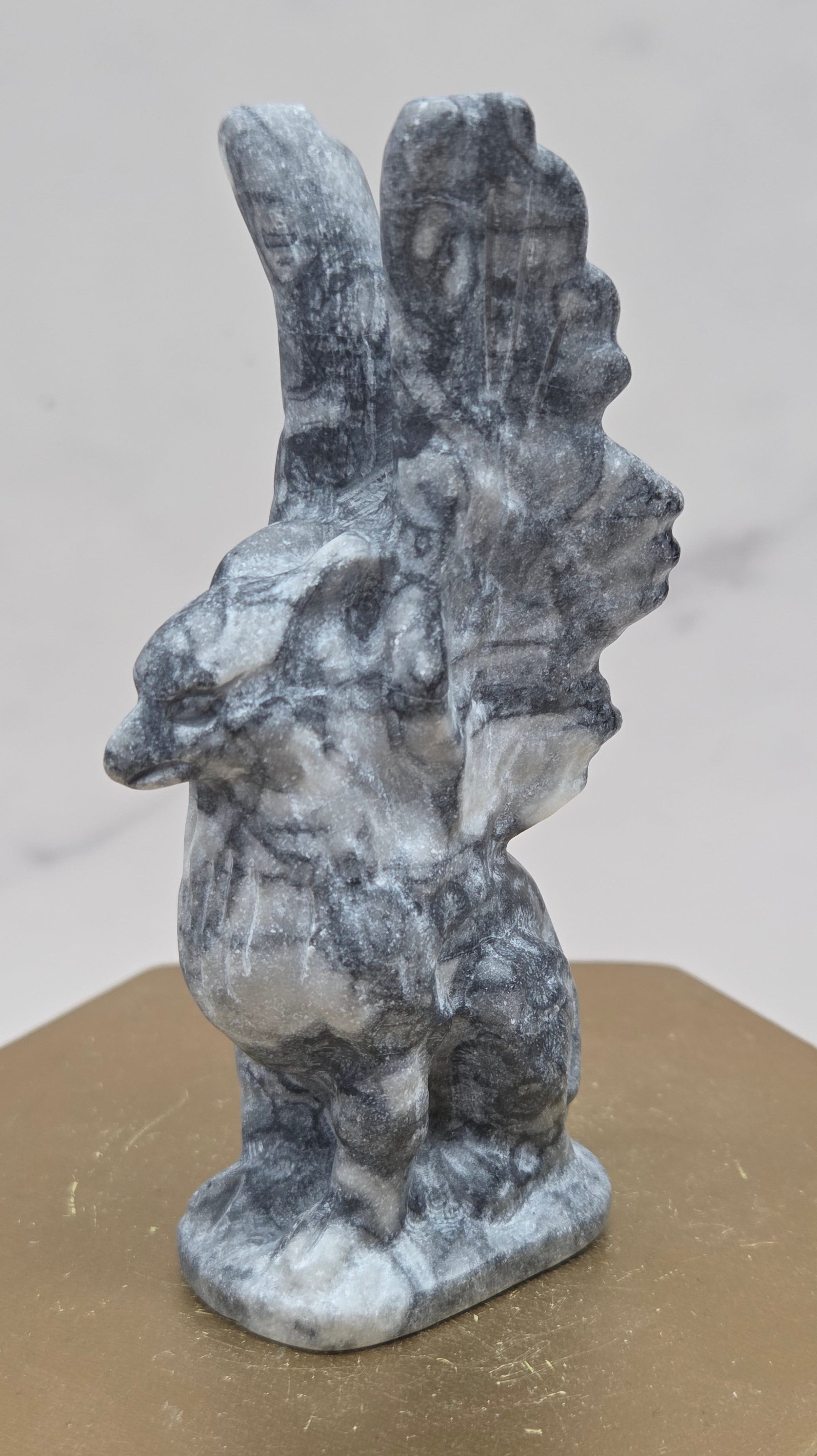 Fossil Jasper griffon carving on a wood stand against a white background