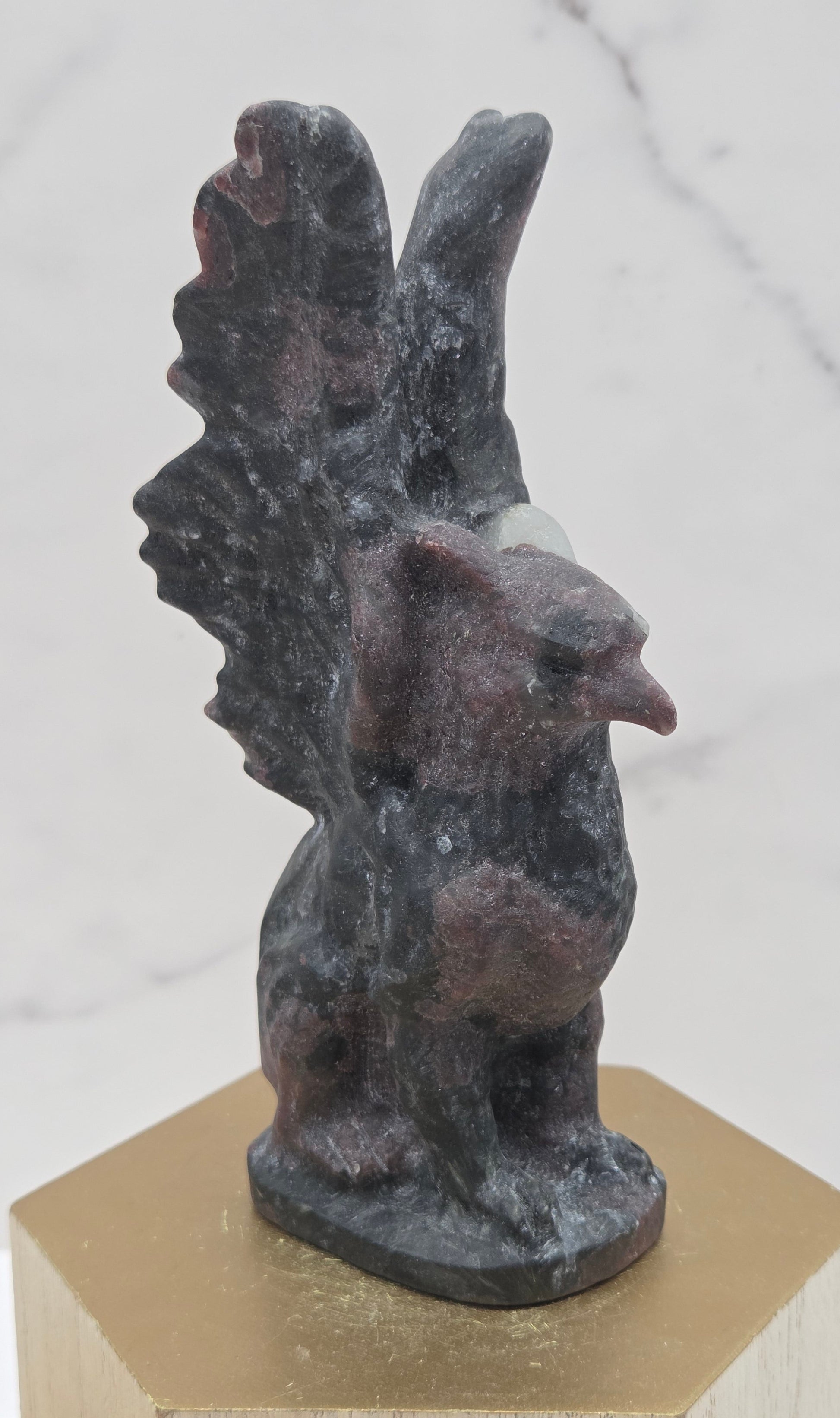 Garnet griffon carving on a wood stand against a white background
