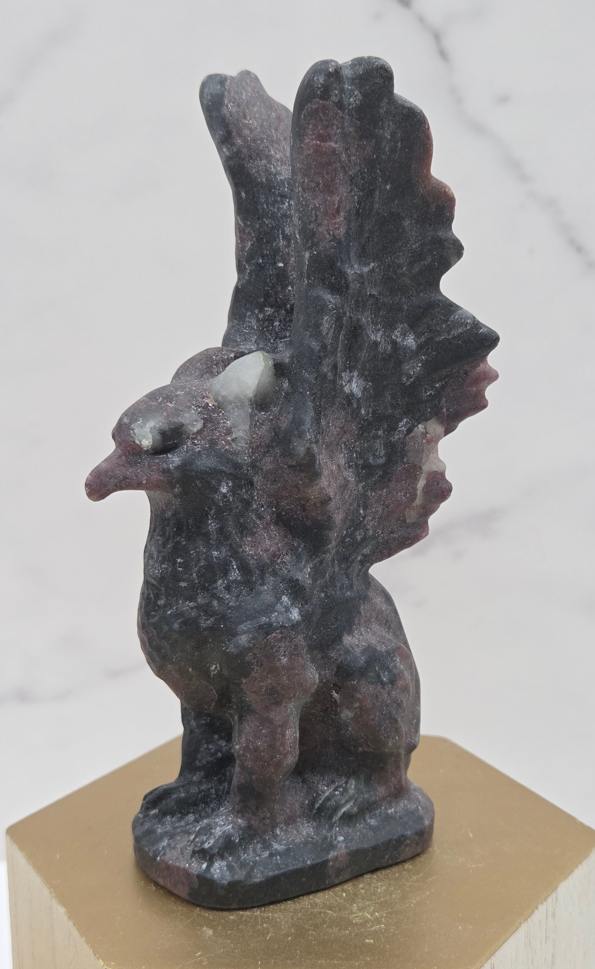 Garnet griffon carving on a wood stand against a white background