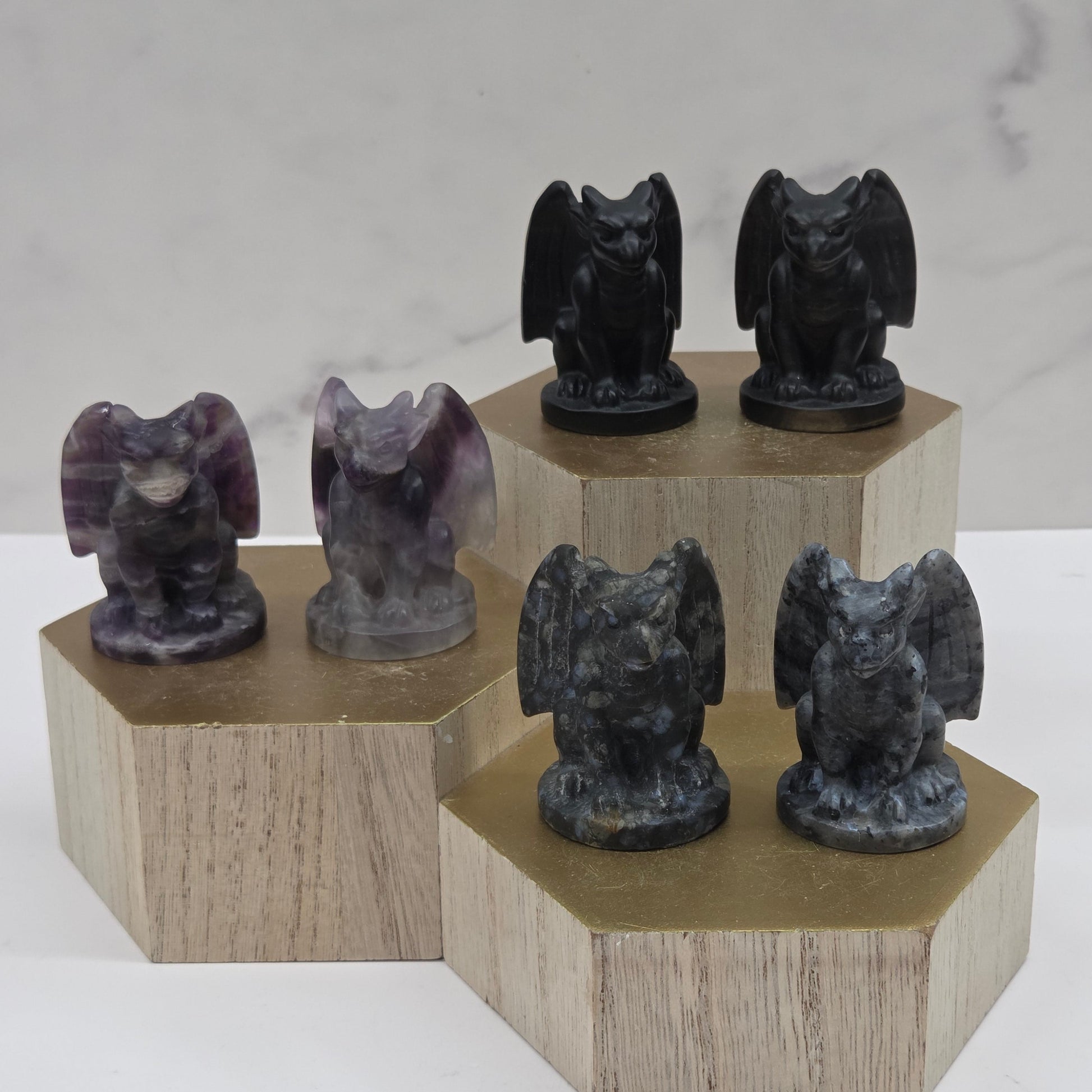 Wooden stand with black and purple gargoyle stone sculptures on a marble background