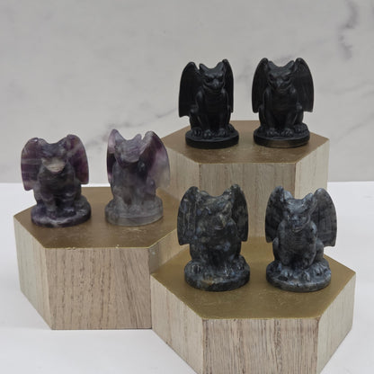 Wooden stand with black and purple gargoyle stone sculptures on a marble background