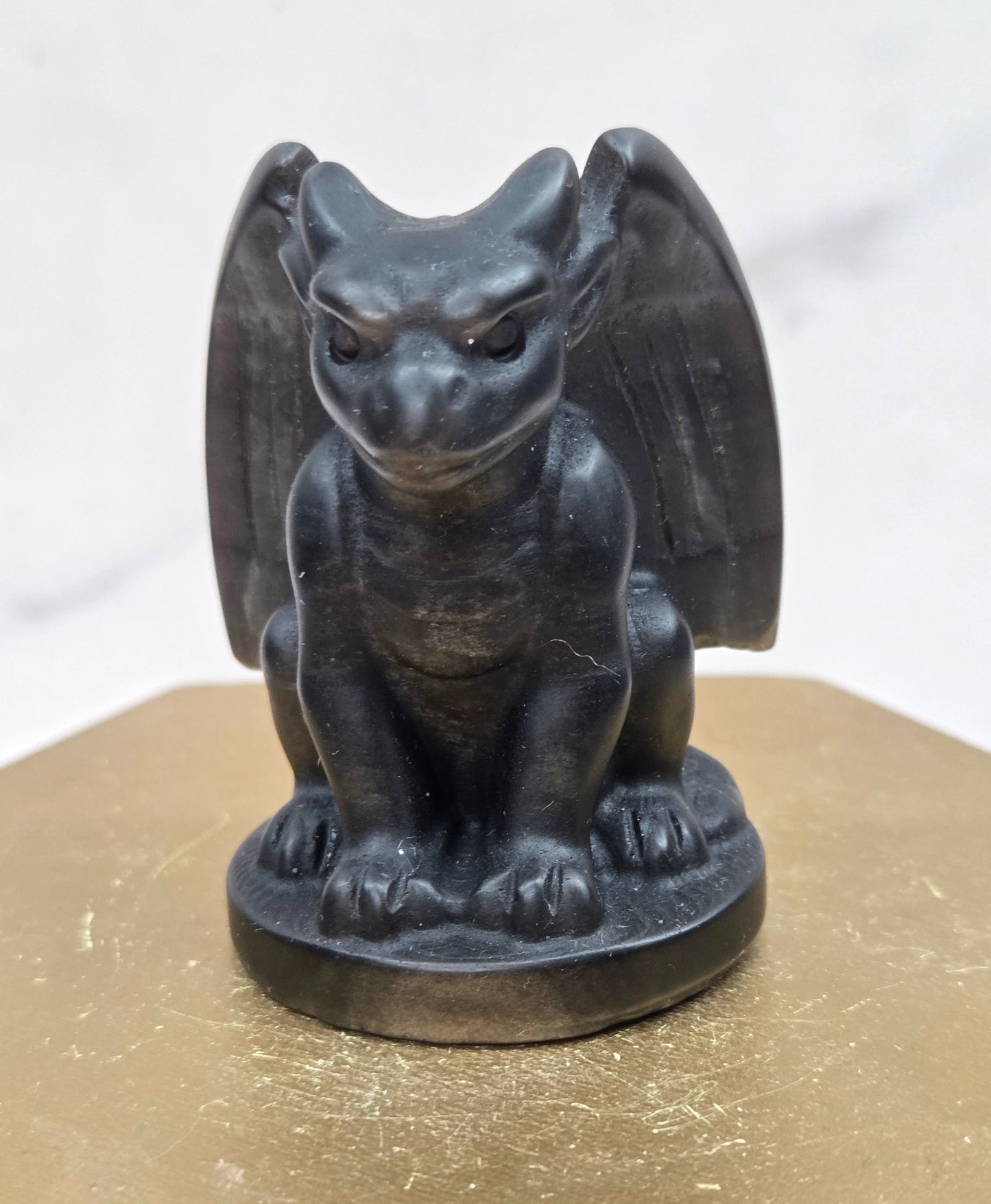 Decorative Obsidian gargoyle carving  on a wooden surface with a white background