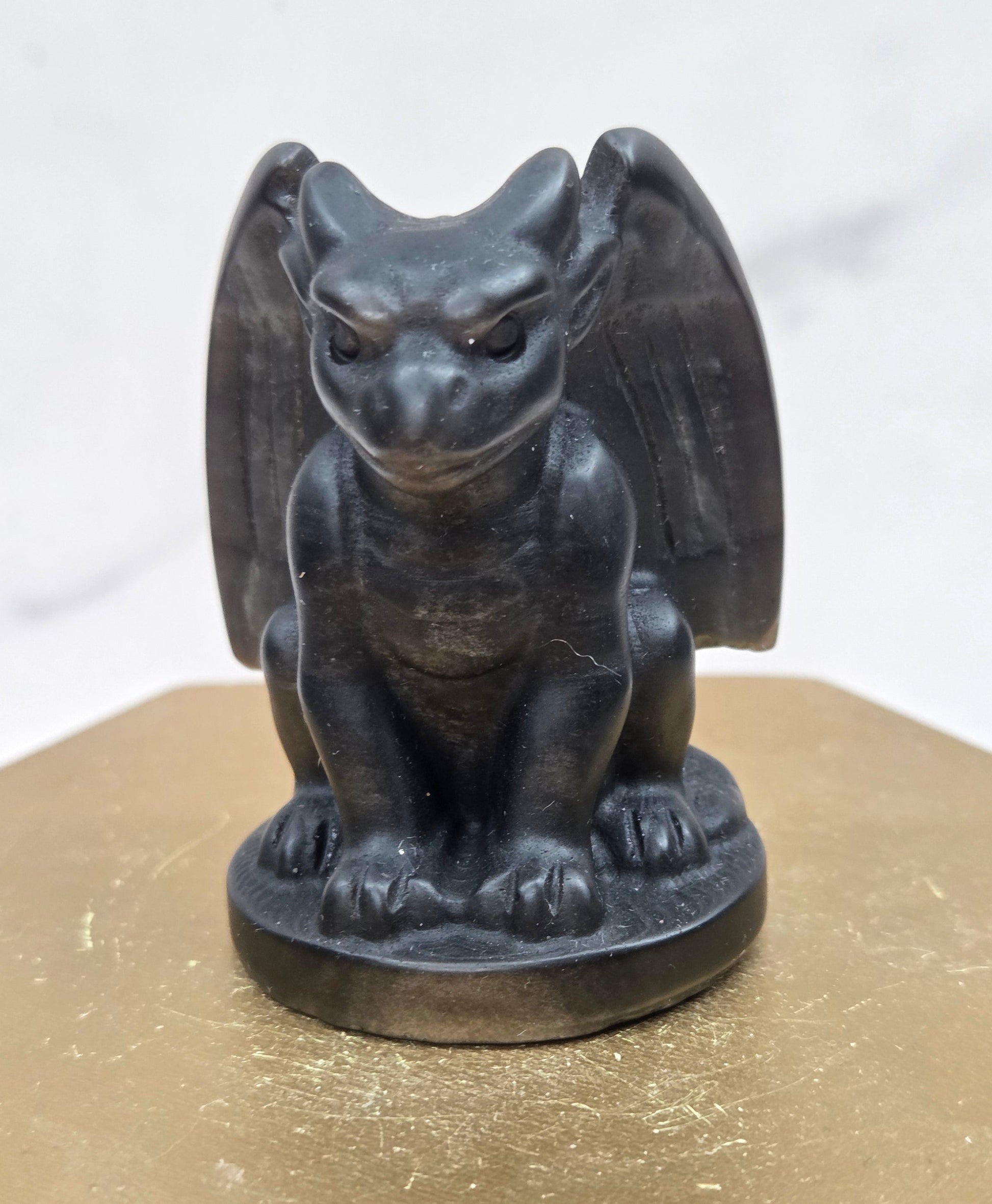 Decorative Obsidian gargoyle carving  on a wooden surface with a white background