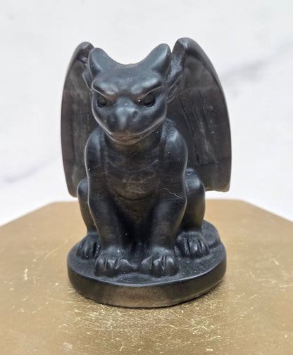 Decorative Obsidian gargoyle carving  on a wooden surface with a white background