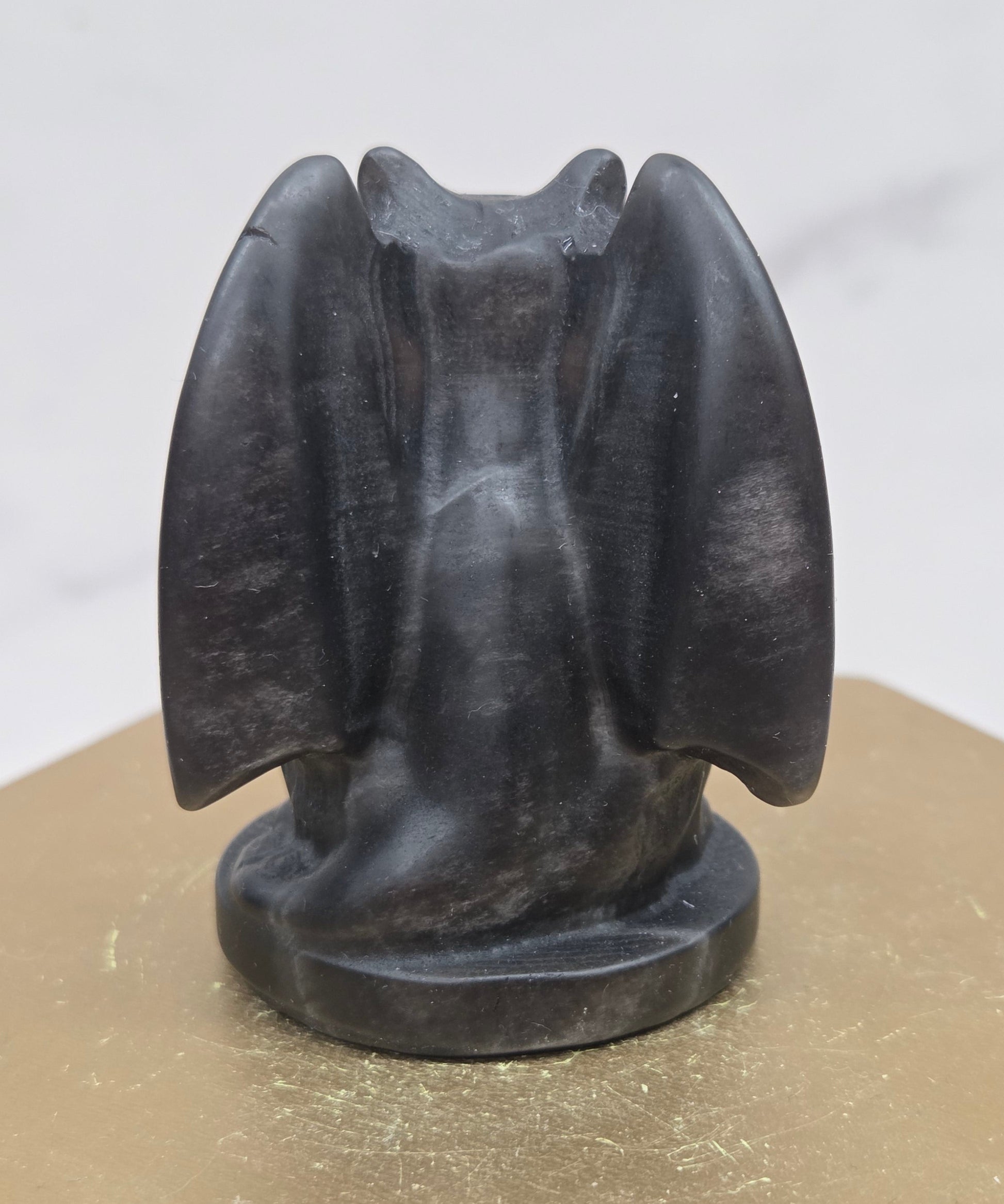 Decorative Obsidian gargoyle carving  on a wooden surface with a white background