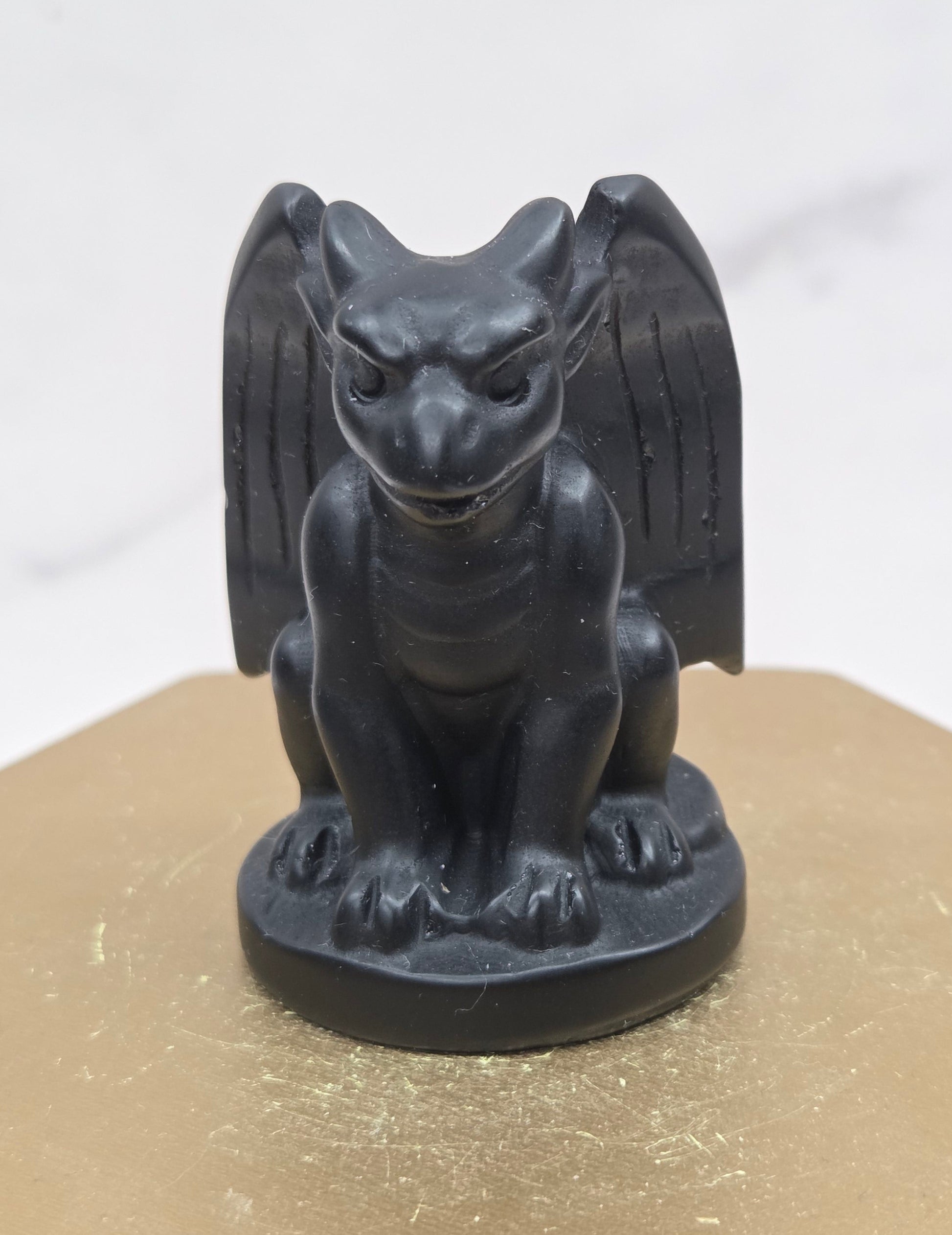 Decorative Obsidian gargoyle carving  on a wooden surface with a white background