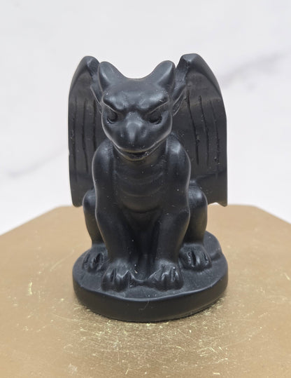 Decorative Obsidian gargoyle carving  on a wooden surface with a white background