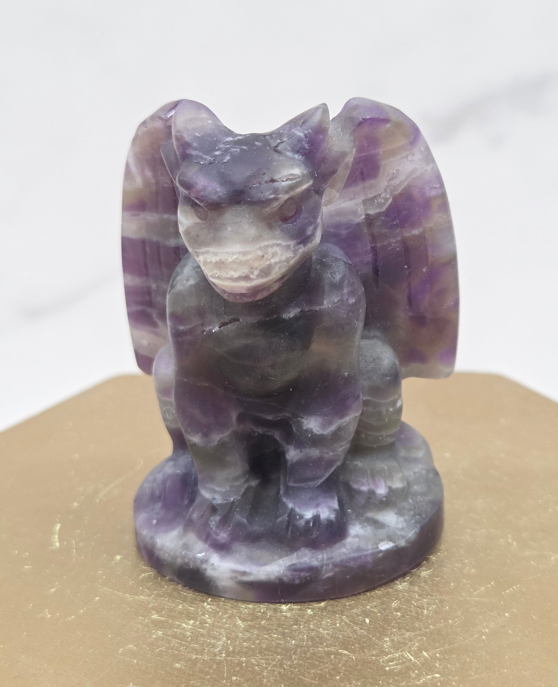 Decorative Amethyst gargoyle carving  on a wooden surface with a white background