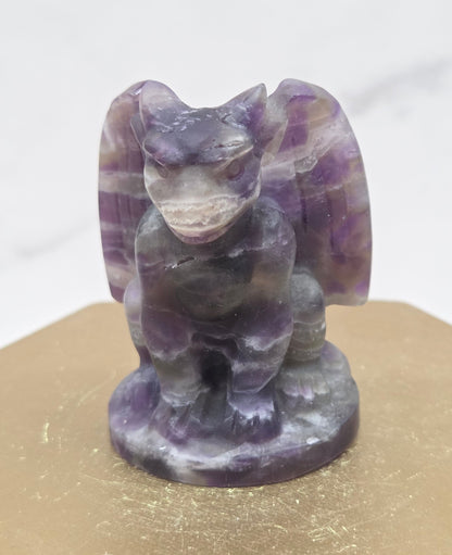 Decorative Amethyst gargoyle carving  on a wooden surface with a white background