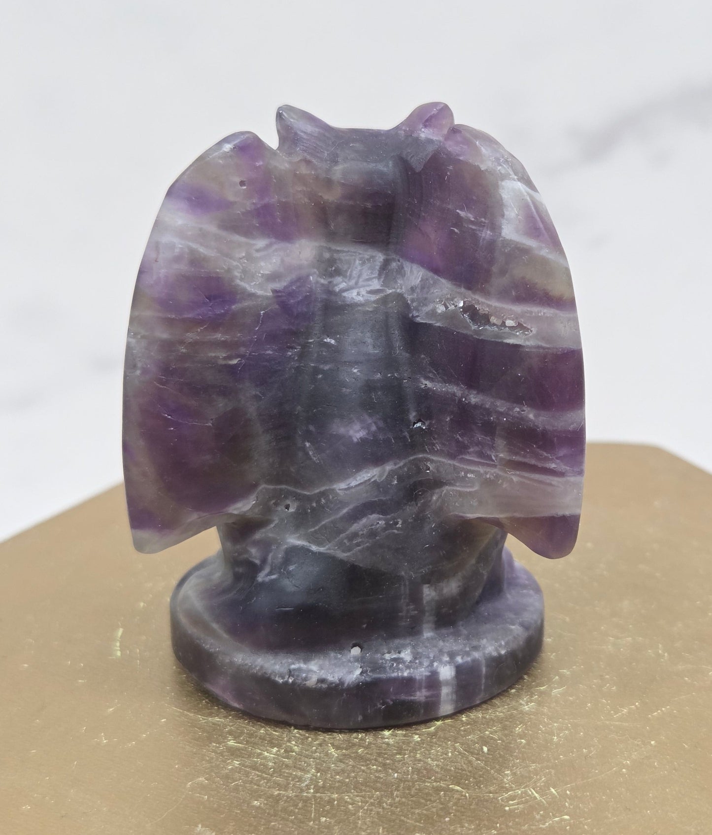 Decorative Amethyst gargoyle carving  on a wooden surface with a white background