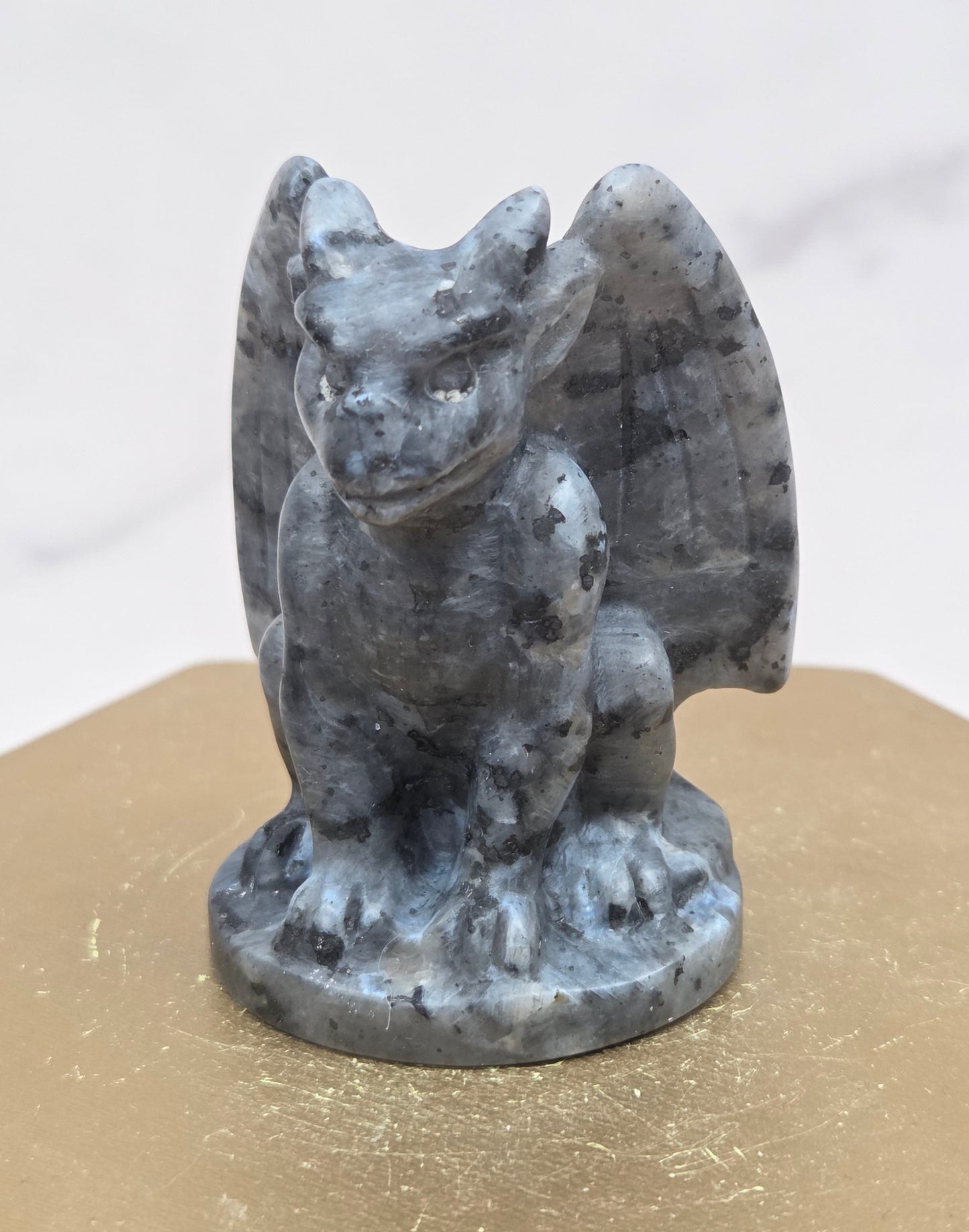 Decorative Larvikite gargoyle carving  on a wooden surface with a white background