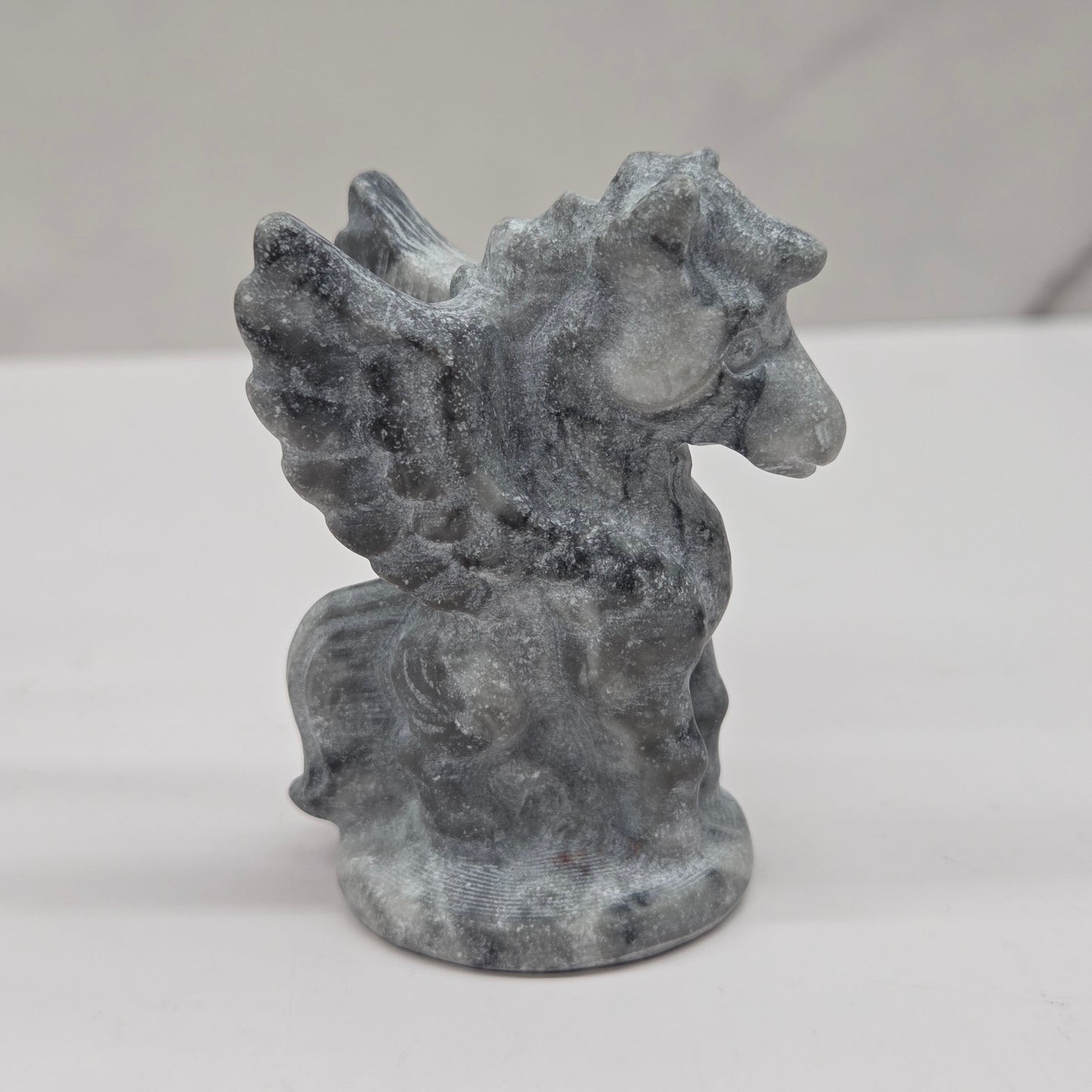 Stone sculpture of a winged creature on a white background