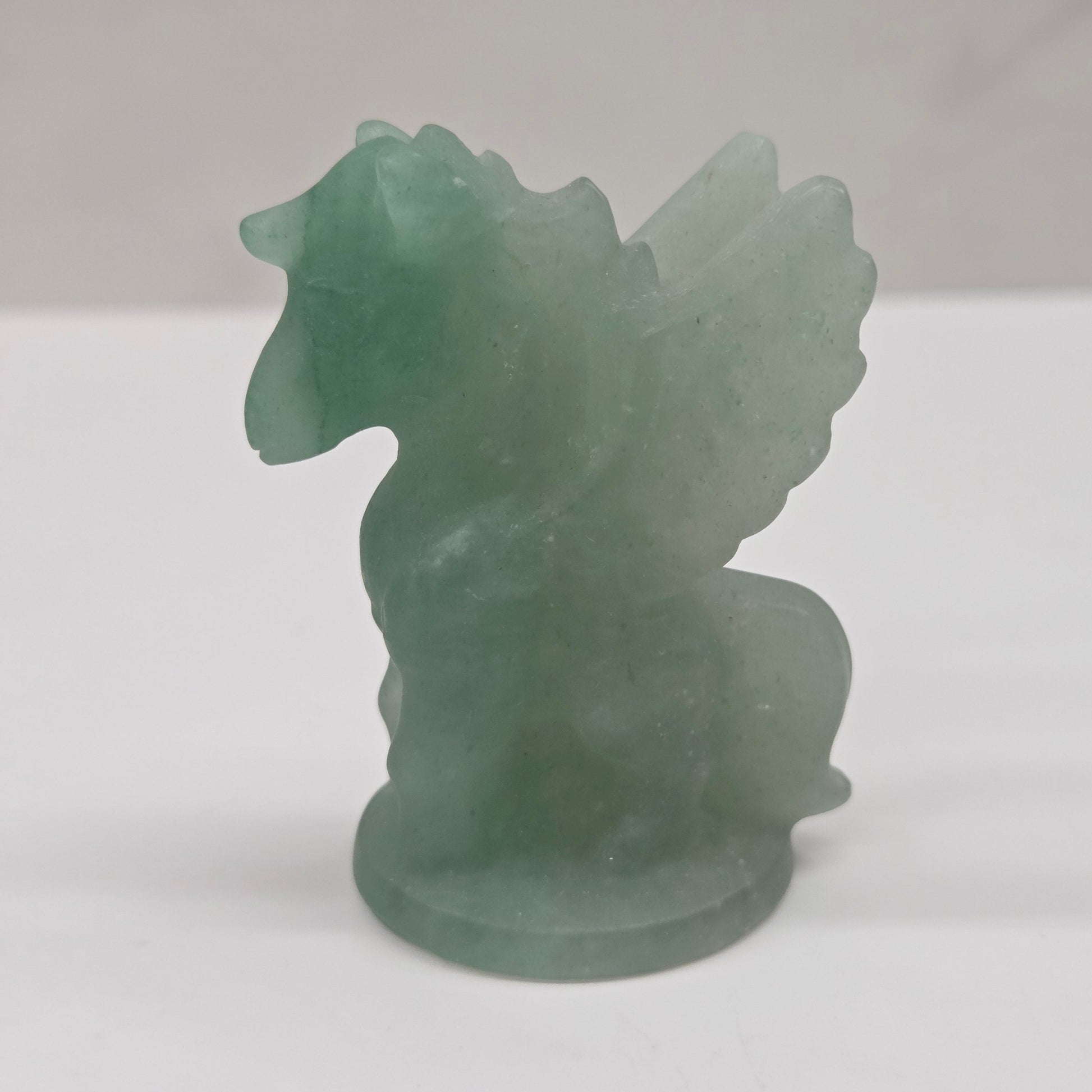 Green stone sculpture of a winged creature on a white background