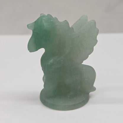Green stone sculpture of a winged creature on a white background