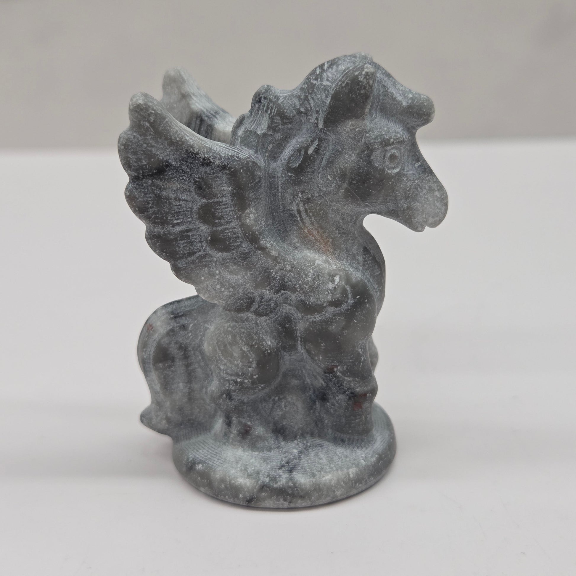 Stone sculpture of a winged creature on a white background