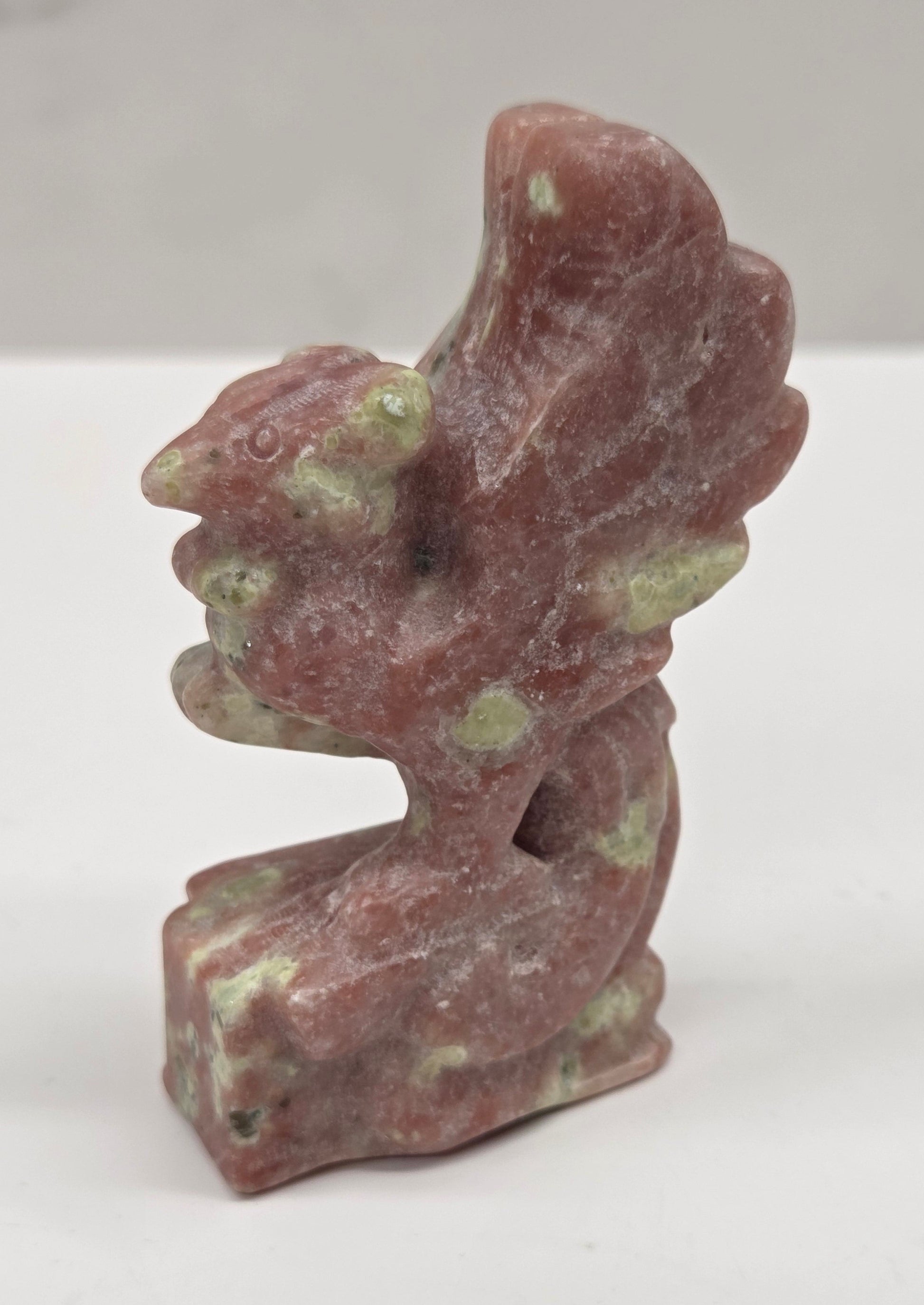 Polished red serpentine stone phoenix carving with a natural pattern on a white background