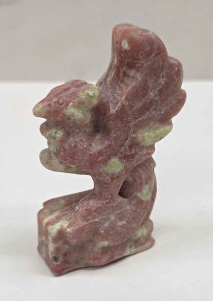 Polished red serpentine stone phoenix carving with a natural pattern on a white background