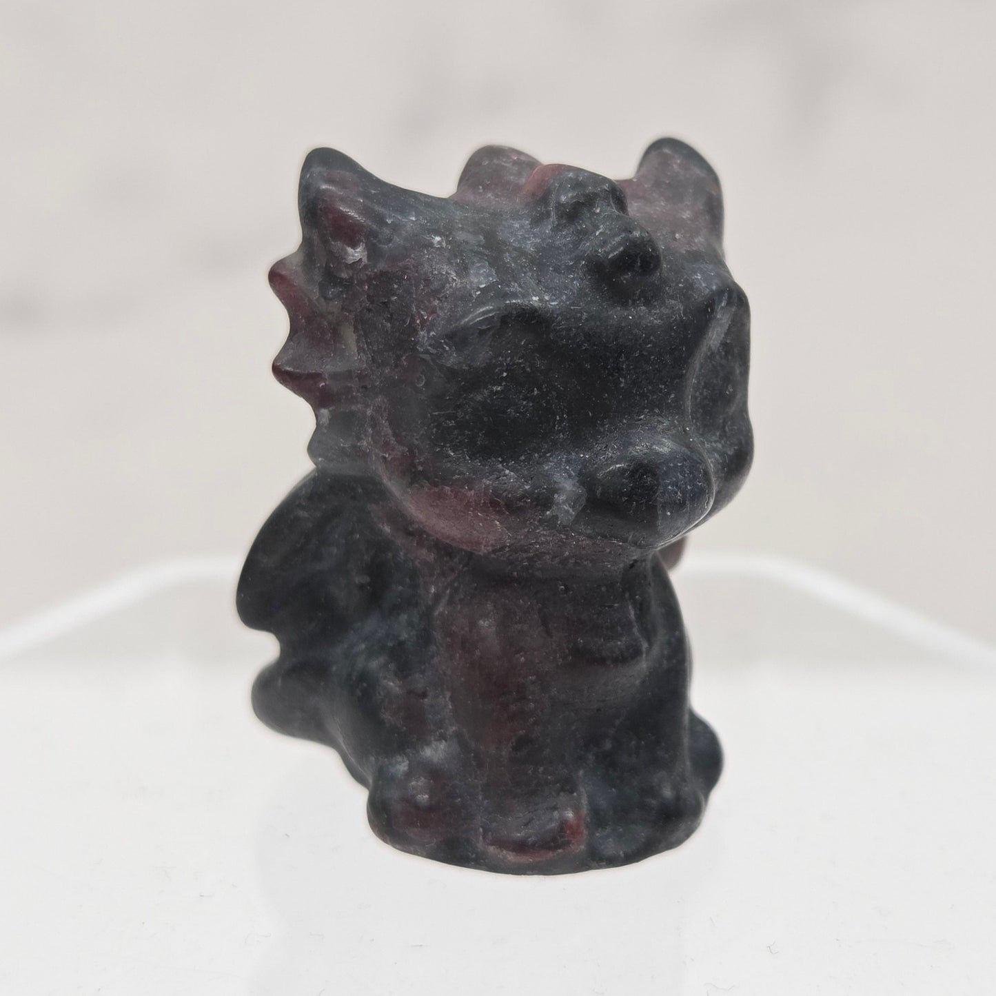 Garnet dragon carving on an acrylic stand against a white background
