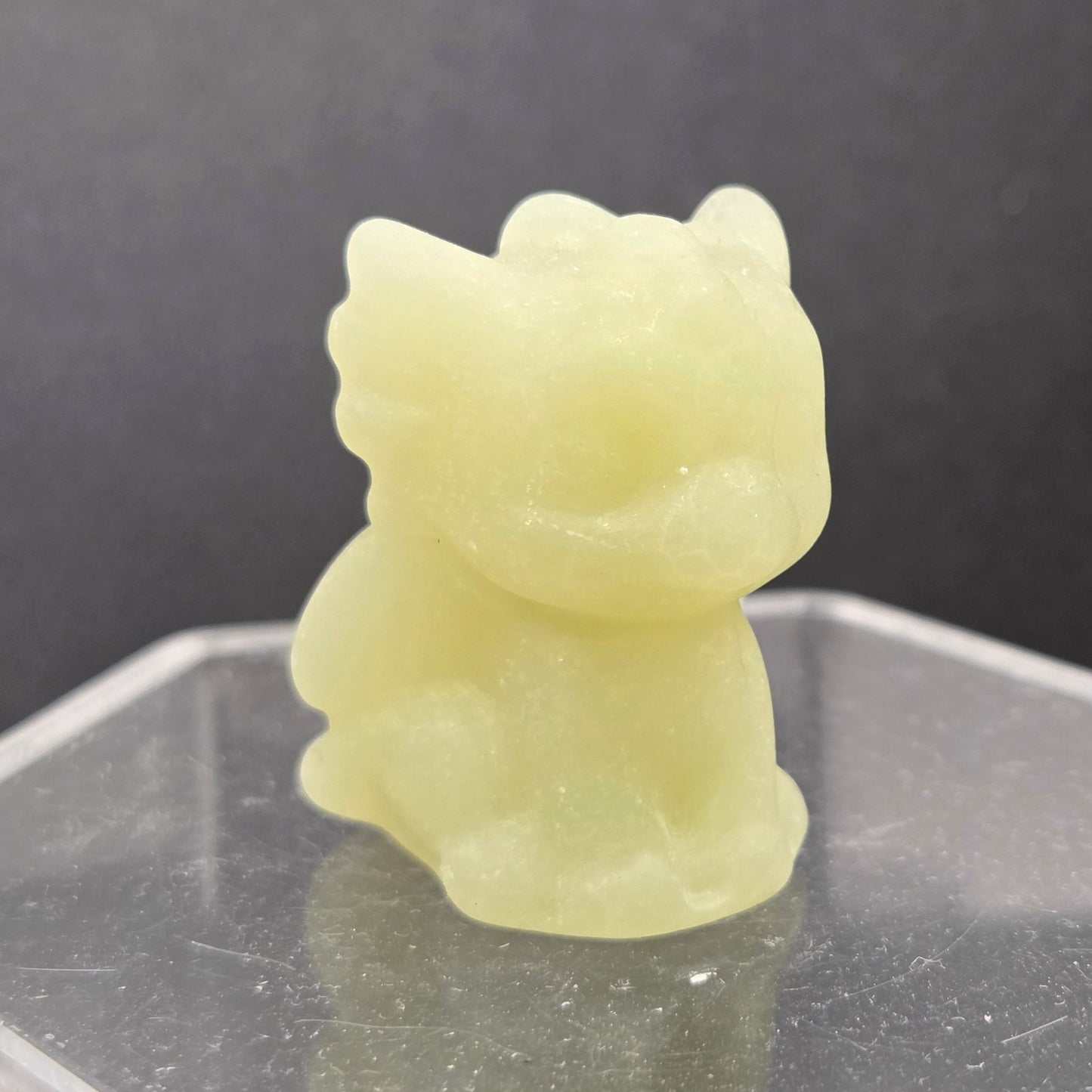 Afghan Jade dragon carving on an acrylic stand against a dark background