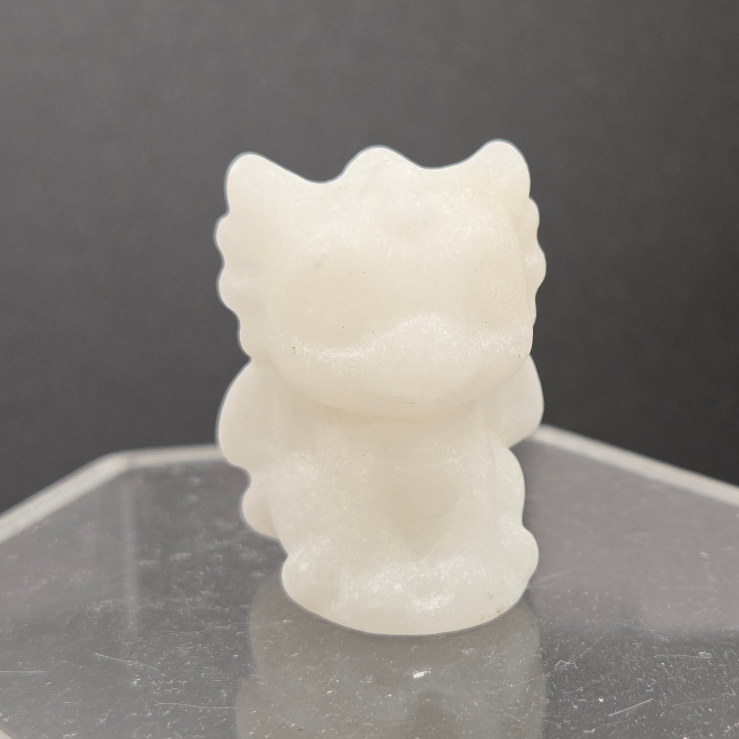 White Jade dragon carving on an acrylic stand against a dark background
