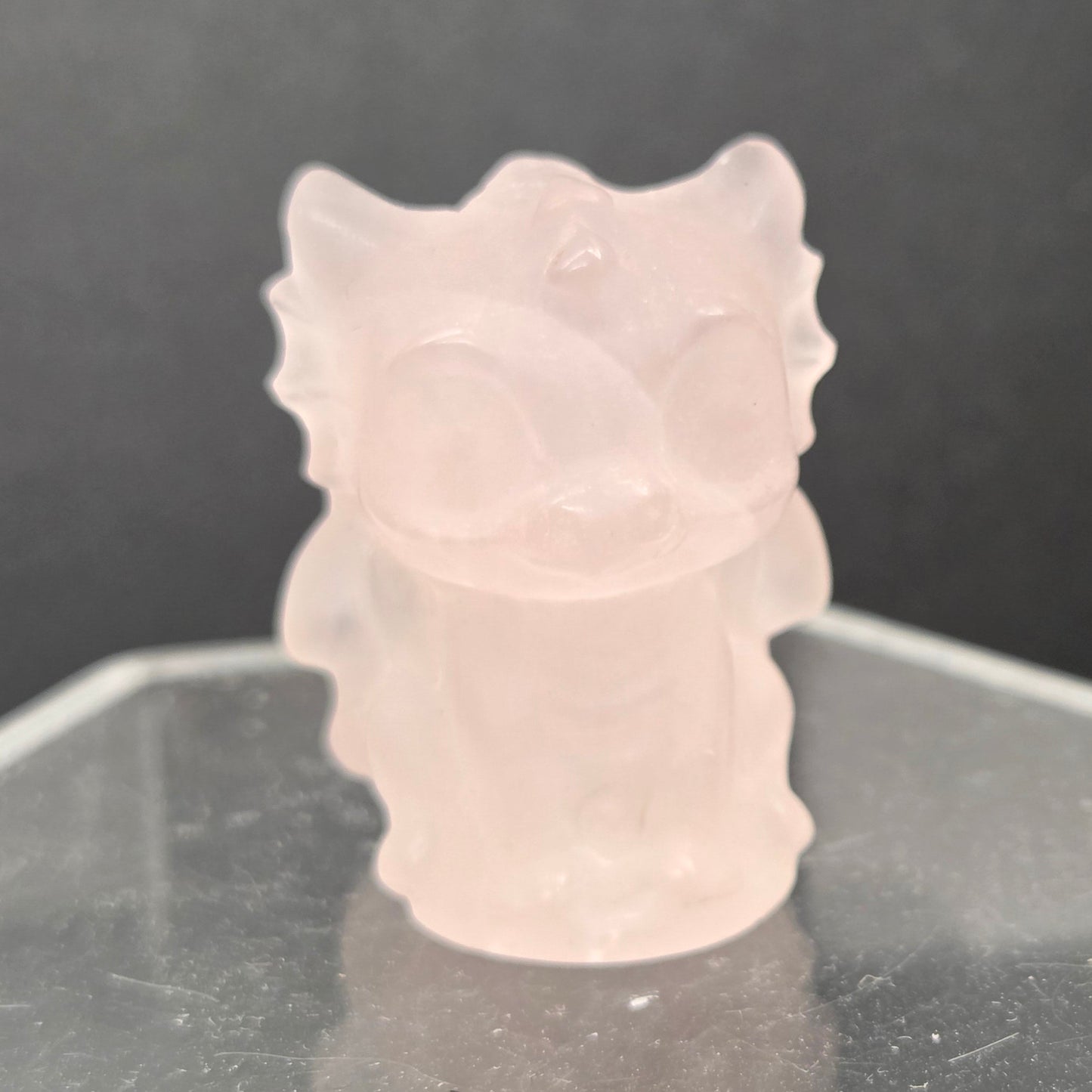 Rose Quartz dragon carving on an acrylic stand against a dark background