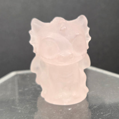 Rose Quartz dragon carving on an acrylic stand against a dark background