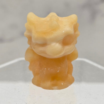 Orange Calcite dragon carving on an acrylic stand against a white background