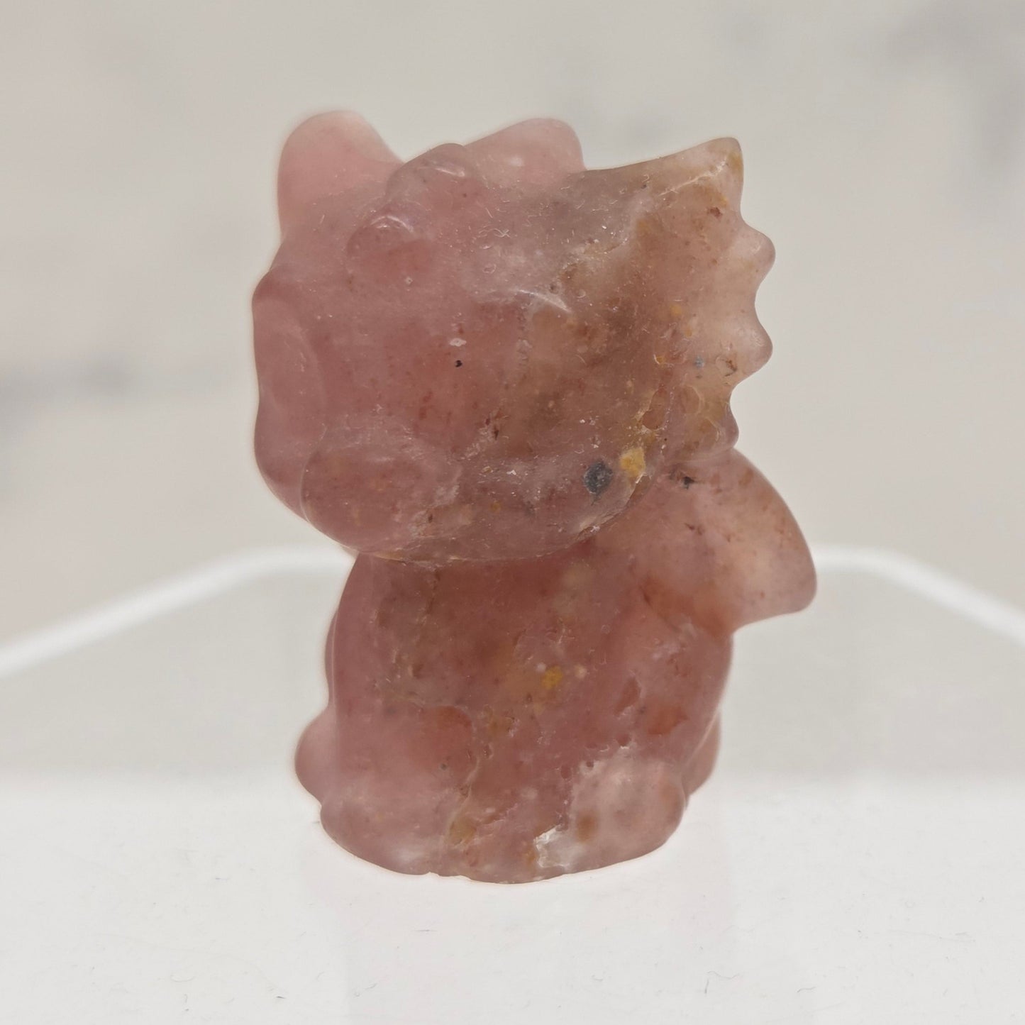 Strawberry Quartz dragon carving on an acrylic stand against a white background