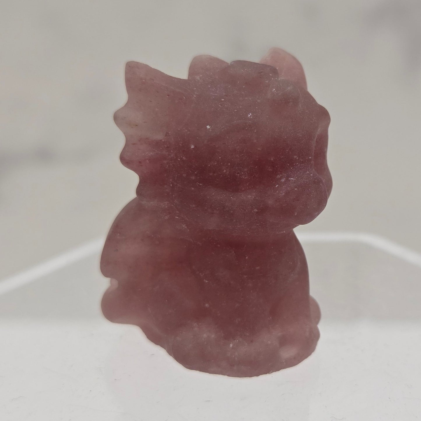 Strawberry Quartz dragon carving on an acrylic stand against a white background