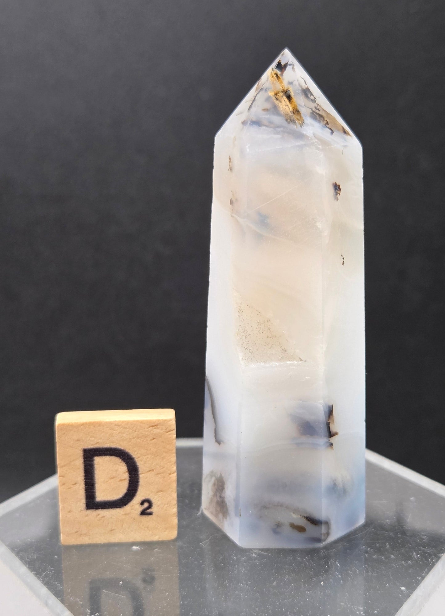 Dendritic Agate tower on an acrylic stand against a dark background