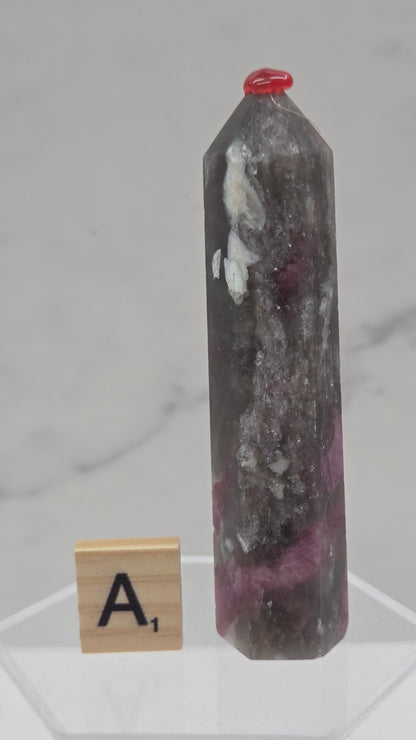Polished Unicorn Stone crystal towers with varying shades of purple and red, showcasing the natural layered pattern of the stones.