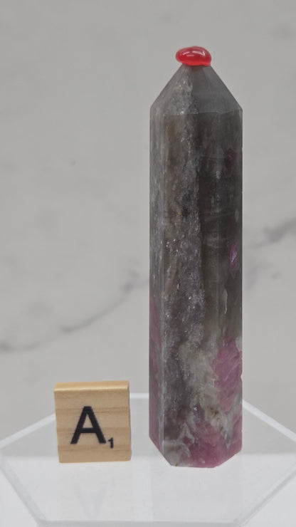 Polished Unicorn Stone crystal towers with varying shades of purple and red, showcasing the natural layered pattern of the stones.