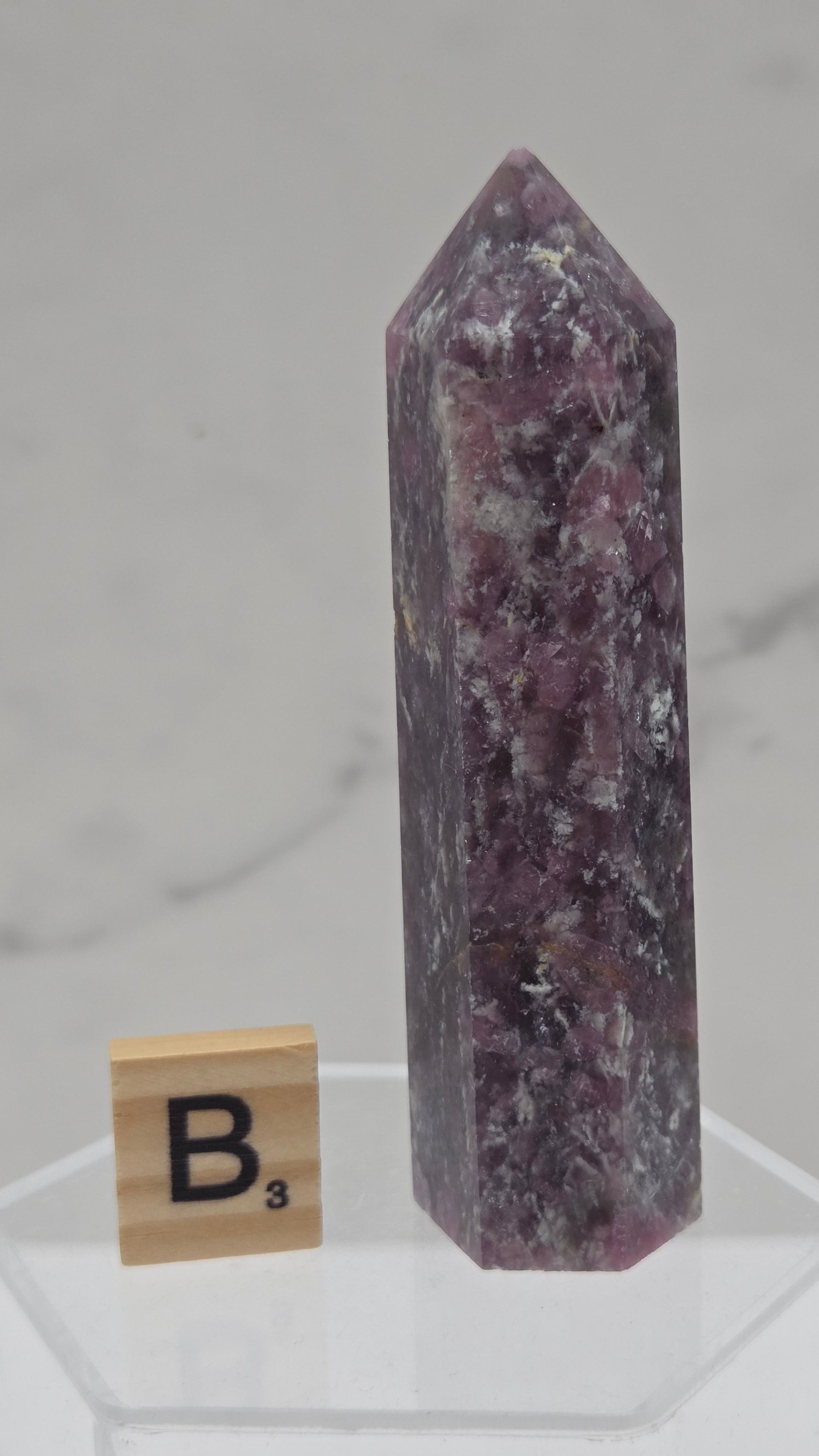 Polished Unicorn Stone crystal towers with varying shades of purple and red, showcasing the natural layered pattern of the stones.