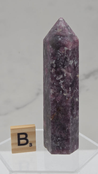 Polished Unicorn Stone crystal towers with varying shades of purple and red, showcasing the natural layered pattern of the stones.