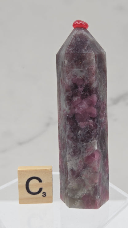 Polished Unicorn Stone crystal towers with varying shades of purple and red, showcasing the natural layered pattern of the stones.