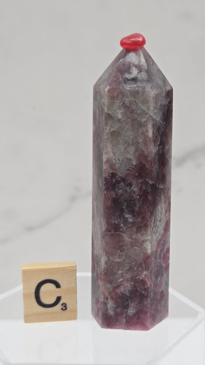 Polished Unicorn Stone crystal towers with varying shades of purple and red, showcasing the natural layered pattern of the stones.
